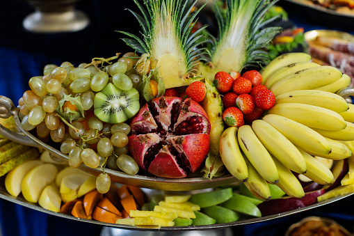 A platter filled with a variety of fresh fruits including grapes, bananas, and pineapple