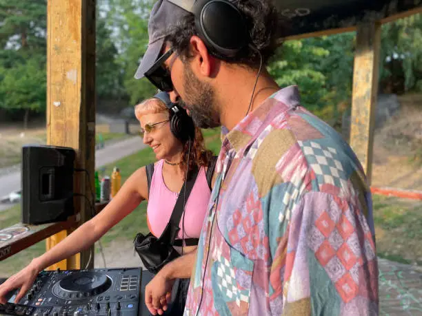 Happy Woman and Man Djing at the park, making music outdoor.