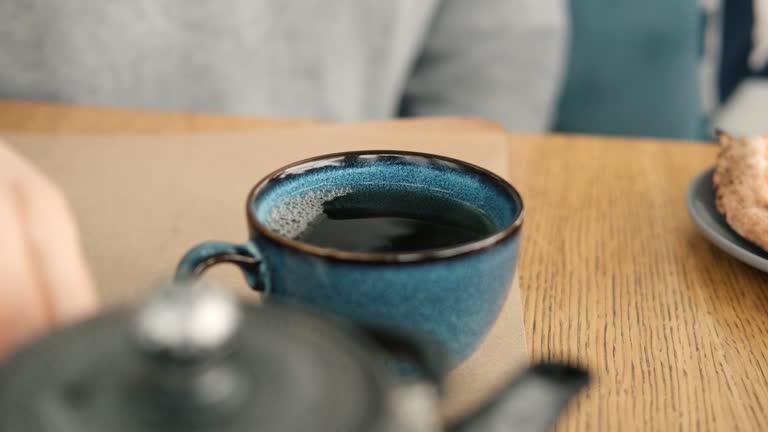 Brewing and Serving Tea. Teapot Pouring Green Tea in Blue Ceramic Cup on Wooden Cafe Table. Two Pottery Handmade Mugs Early in the Morning. Trendy Authentic Porcelain Set. Breakfast Concept. Tea Time.