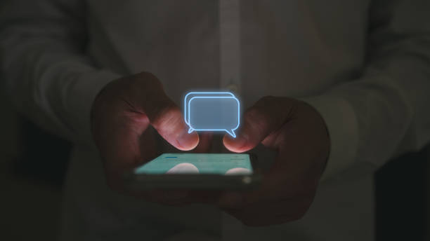 istock Social media marketing concept. low light shot Man hand using smartphone typing, chatting conversation in chat box icons pop up 2015222564