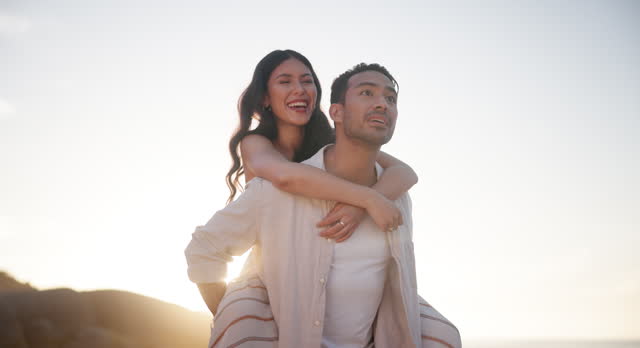 Happy couple, beach and walk with piggyback on holiday, sunset and together for sightseeing in nature. Man, woman and talking for summer love in commitment and honeymoon vacation with travel by ocean