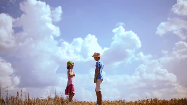 Tender Moment as a Boy Presents a Flower to a Girl on a Majestic Hilltop Against the Expansive Skyline