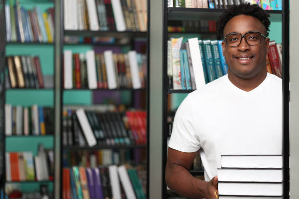 istock Positive african librarian putting new interesting books on shelves 2015272950