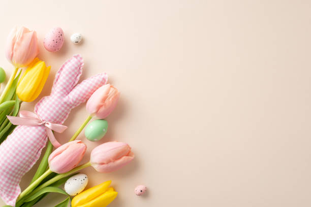 istock Bunny Bliss: Vibrant eggs, playful bunny toy, and blooming tulips arranged in top view on soft beige background. This Easter-inspired image provides perfect canvas for your text or promotional content 2015274512