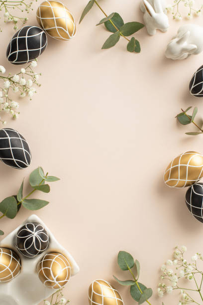 istock Deluxe Easter concept: Vertical top view of luxurious black and gold eggs in ceramic holder, hare figurines, eucalyptus, gypsophila, arranged on pastel beige background, with blank space for text 2015274561