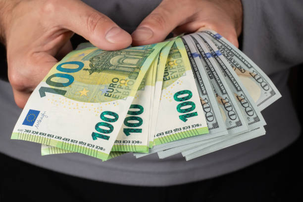 istock 100 Euros and 100 dollars banknotes in men hands. Close up 2015280564