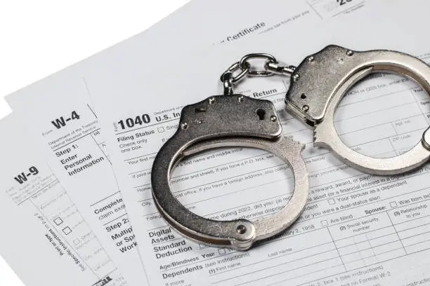 Photo of Handcuffs over Tax forms, concepts: Tax fraud or Slave to the Taxes