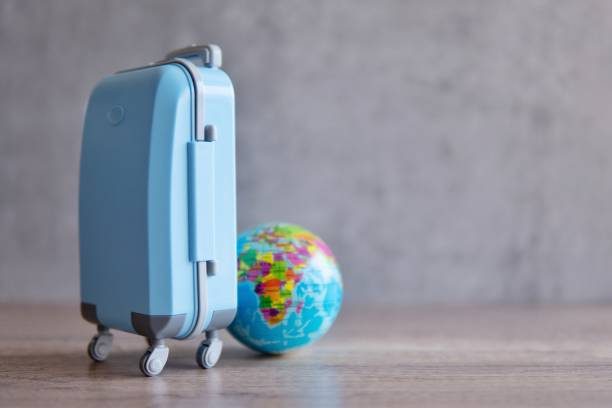 istock A blue luggage on a wooden table next to a globe. 2015299176