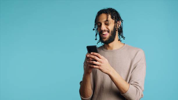 istock Man texting friend using smartphone, laughing at funny joke, studio background 2015310325