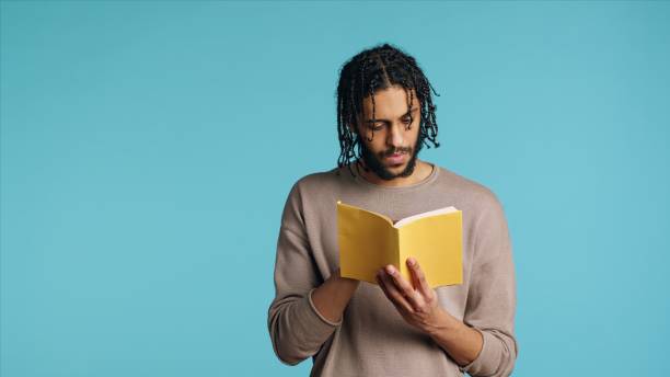 istock Man reading newly released hardcover book from publisher, studio background 2015314724