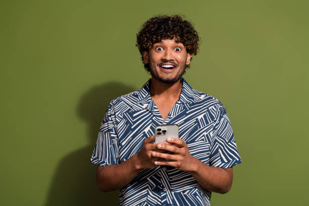 istock Photo of funky impressed man dressed print shirt texting modern gadget empty space isolated green color background 2015320718
