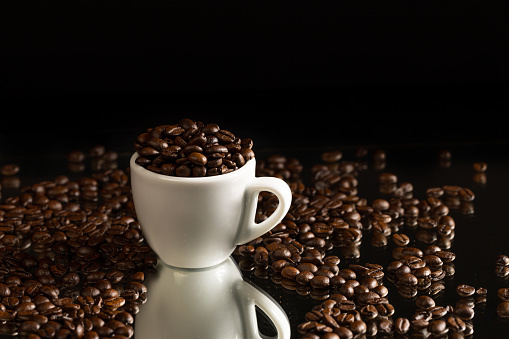 white espresso cup full with coffee beans