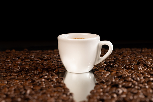 white coffee cup with espresso and coffee beans in background