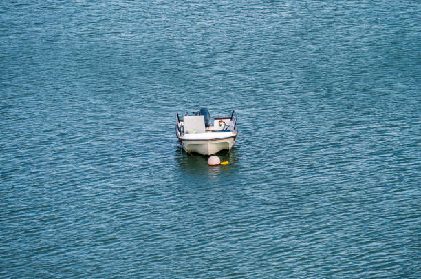 A boat anchored at shallow water in the sea with gentle waves