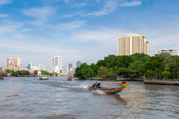 Bangkok, Thailand - 29 December, 2023: tourists ride on a wooden longtail boat decorated with flower garlands on the Chao Phraya River at Bangkok, Thailand