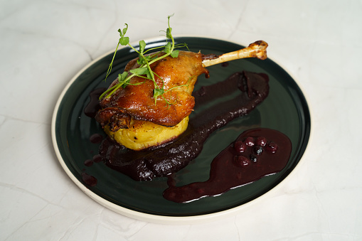 Roasted duck leg on mashed potatoes with onion, purple cabbage cream and blueberry jus