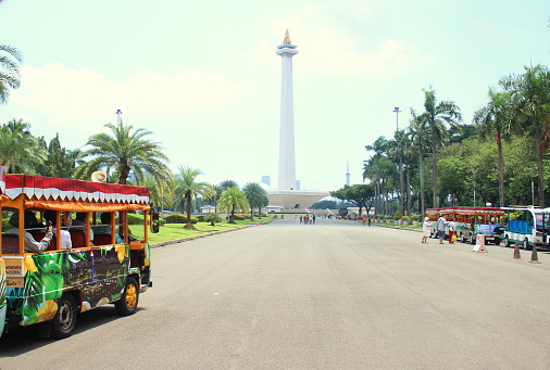 Jakarta City, Indonesia - March 7, 2023 - A simple tourist train takes visitors around the National Monument or Monas Monument area in the center of Jakarta, Indonesia. This shuttle service is operated free of charge.