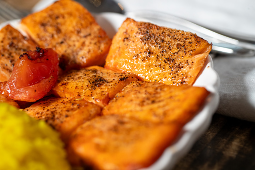 Macro image of Salmon pieces with a roasted tomoato