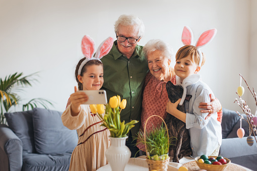 Grandparents taking selfie with grandchildren before traditional easter lunch. Recreating family traditions and customs. Concept of family easter holidays.
