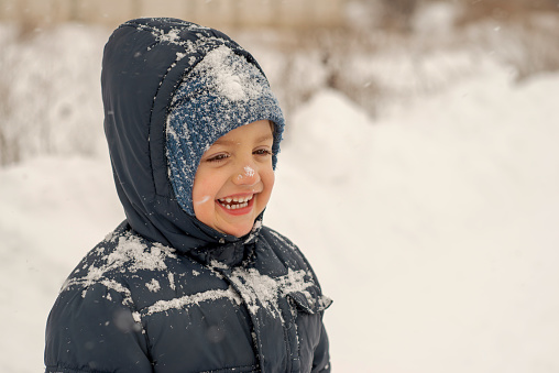 Cute smiling snowy boy enjoying winter season