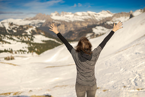 Young woman enjoying a view of a ski resort around Sela mountain, Selaronda, Dolomites, Italy