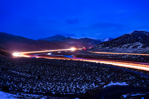 Dusk Light Trails at Night Along Intersate - Interstate 70 in Western Colorado along the Colorado River. Light trails during long exposure with stormy snowy skies captured at blue hour dusk.