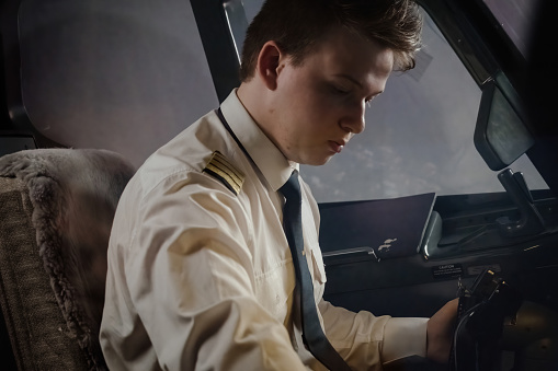 Pilot expertly maneuvers airplane during night flight. Young captain in uniform effortlessly pilots airplane to destination
