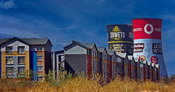 Soweto, Johannesburg, South Africa - August 19, 2018 : The decommissioned Soweto Towers (or Orlando Towers) behind residential buildings. Originally the site of a coal fired power station, the Orlando Towers have become one of the most distinctive landmarks in the neighborhood of Soweto. Nowadays the site is used for bungee and BASE jumping.