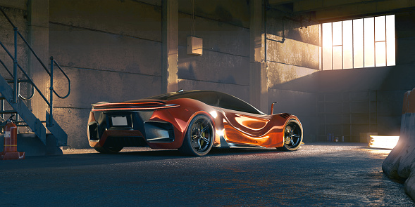 Rear view of a generic red electric sports car parked indoors in a large industrial building facing a window with golden afternoon light streaming in. The car is also lit by an electric light on the tarmac floor.
