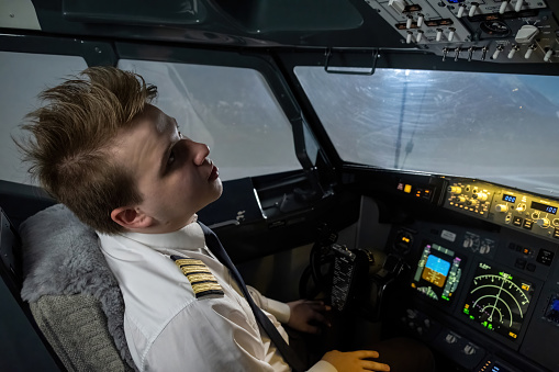 Pilot with mohawk hairstyle looks at dashboard in cockpit. Modern captain eyes scanning array of instruments with focused precision
