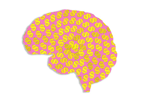 Pink human brain shaped filled with spinning gold dollar sign pattern on white.