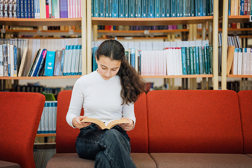 Middle school student reading a book in the school library