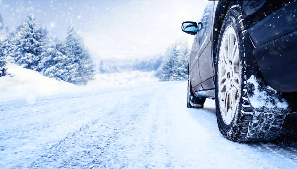 Car tires on winter road covered with snow close-up Winter tire closeup. Car on snowy road with beautiful landscape. blizzard stock pictures, royalty-free photos & images