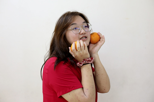 Portrait of an Asian teenage girl holding tangerine fruit. Tangerine fruit signifies Gold in Chinese culture and widely consumed especially Chinese New Year celebration.