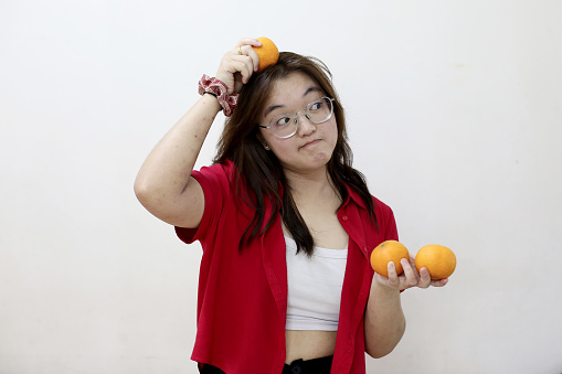 Portrait of an Asian teenage girl holding tangerine fruit. Tangerine fruit signifies Gold in Chinese culture and widely consumed especially Chinese New Year celebration.