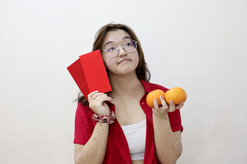 Portrait shot of an asian female holding mandarin oranges and smiling