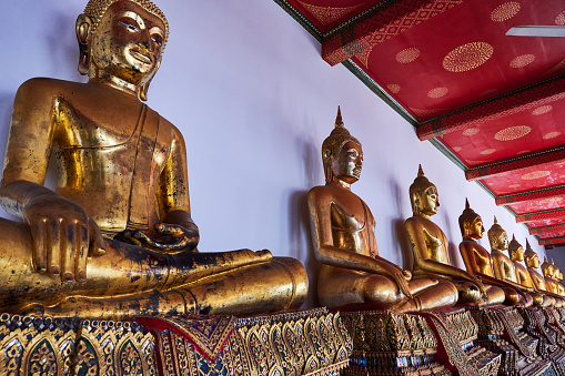 Gold coated buddhist staues lined up at Wat Pho temple. Phra Nakhon District. Bangkok. Thailand.