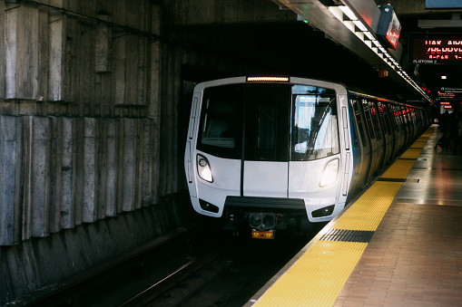 The lightrail system in San Francisco, California, arriving through an underground tunnel to a train station loading platform.
