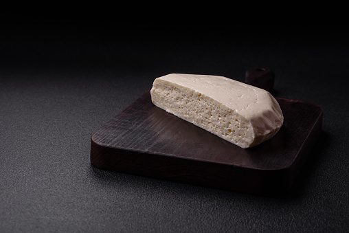 Delicious fresh white young cheese from cow's or sheep's milk on a dark concrete background
