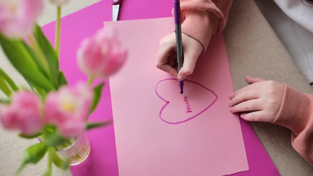 Mothers Day. I love you mom. DIY postcard.Message to mom. child makes a card for his mother
Flowers and cards for mom.Daughter draws a card for mom.