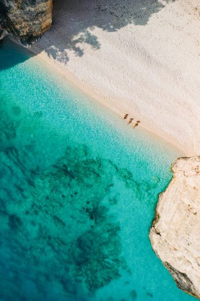 istock People relaxing and aunbathing on beach with clear sea water 2015650967