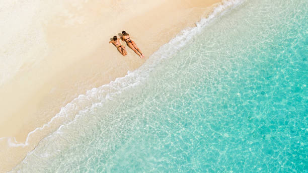 istock Two beautiful young women relaxing and sunbathing on beach. Aerial view 2015651478