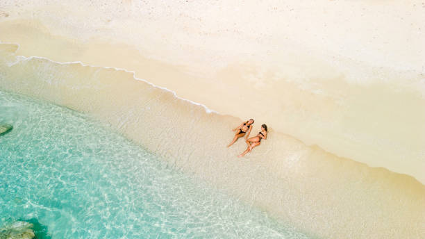 istock Two beautiful young women relaxing and sunbathing on beach. Aerial view 2015651486