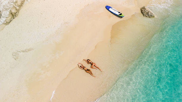 istock Two beautiful young women relaxing and sunbathing on beach. Aerial view 2015651489