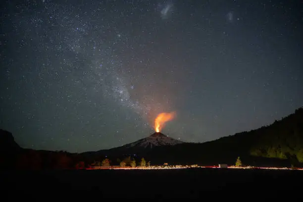 The active volcano Villarrica during the night with a starry sky with a passing car near Pucón in Chile