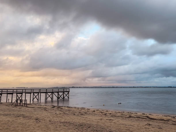 Empty wooden pier to the Ria de Aveiro in Portugal, with dramatic sky and calm water. Torreira, Murtosa - Portugal.