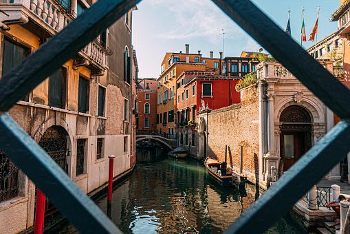 View through a Fence of a Scenic Canal with Vibrant Colored Buildings in Venice, Italy