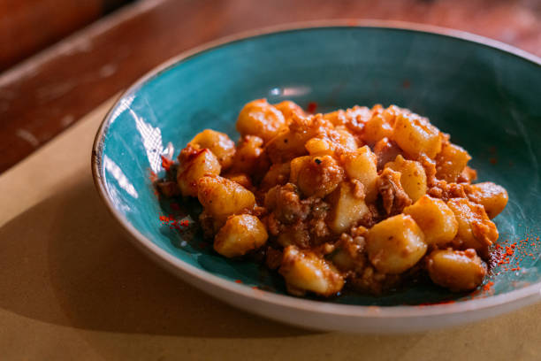 Italian pasta gnocchi on a plate with bolognese sauce over stone background with copy space.