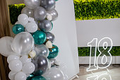 Arch decorated with green, grey, white balloons and flowers