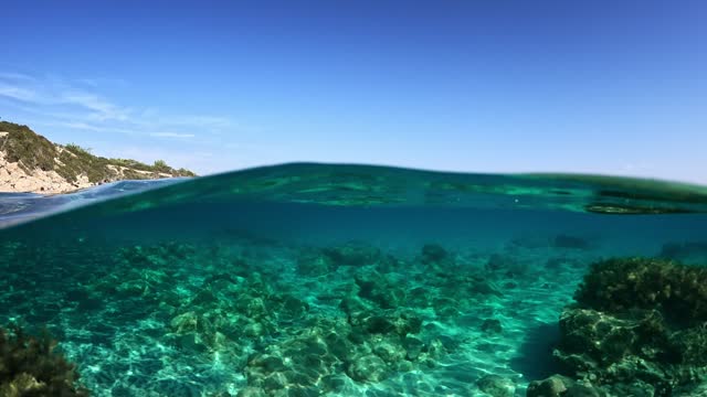 Crystal clear blue water in Mediterranean Sea on the coast of Cyprus. Half underwater slow motion shot of clear turquoise water